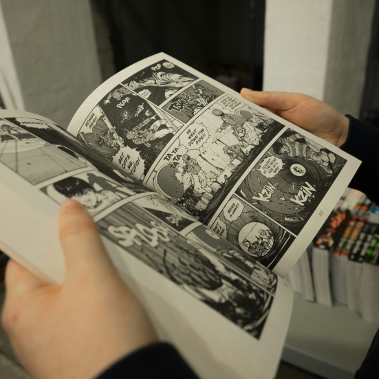 To hænder holder en åben manga-bog.