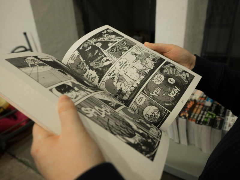 To hænder holder en åben manga-bog.