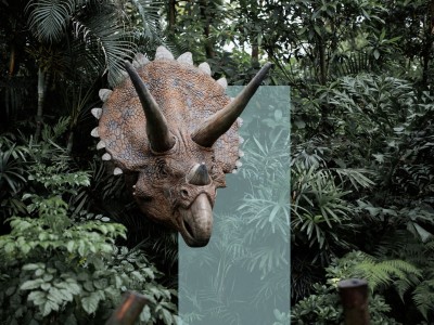 En hornet dinosaur stikker hovedet frem mellem tæt, grøn jungle.